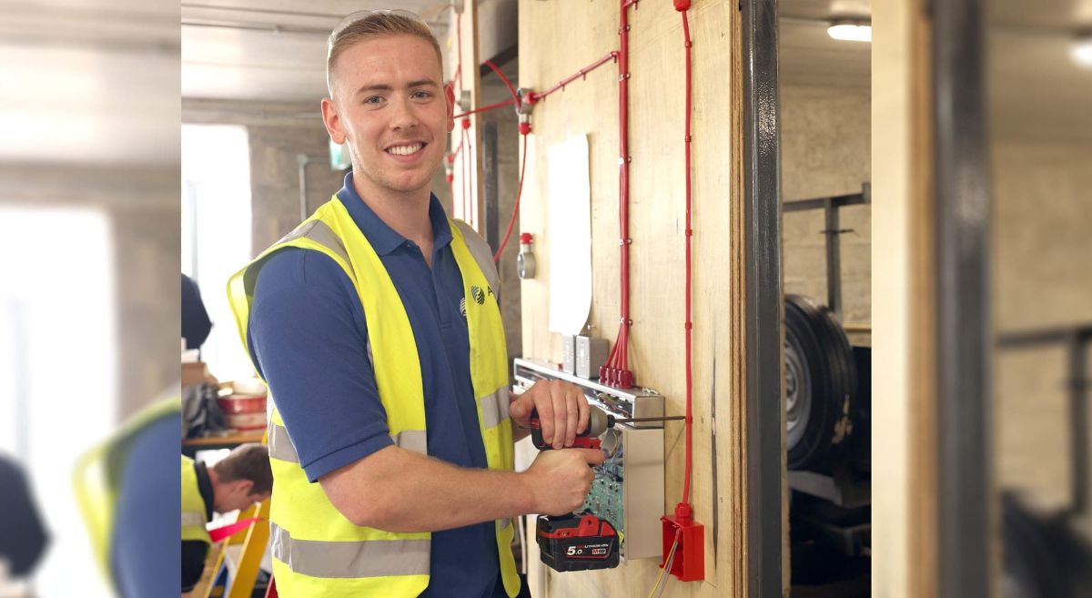 Picture of young male smiling and holding a drill.